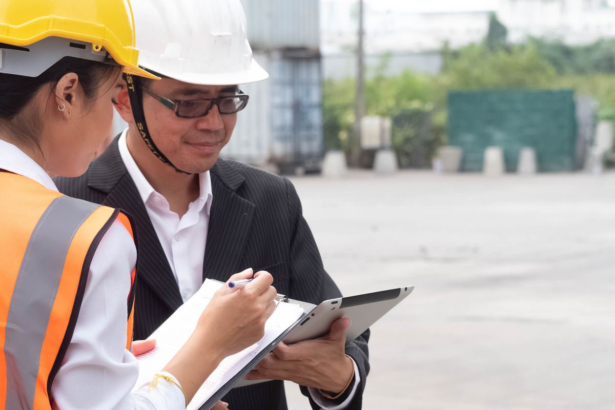 Two site personnel in high-visibility PPE reviewing paperwork together
