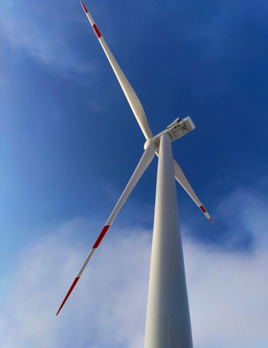 A wind turbine seen from below against a cloudy sky