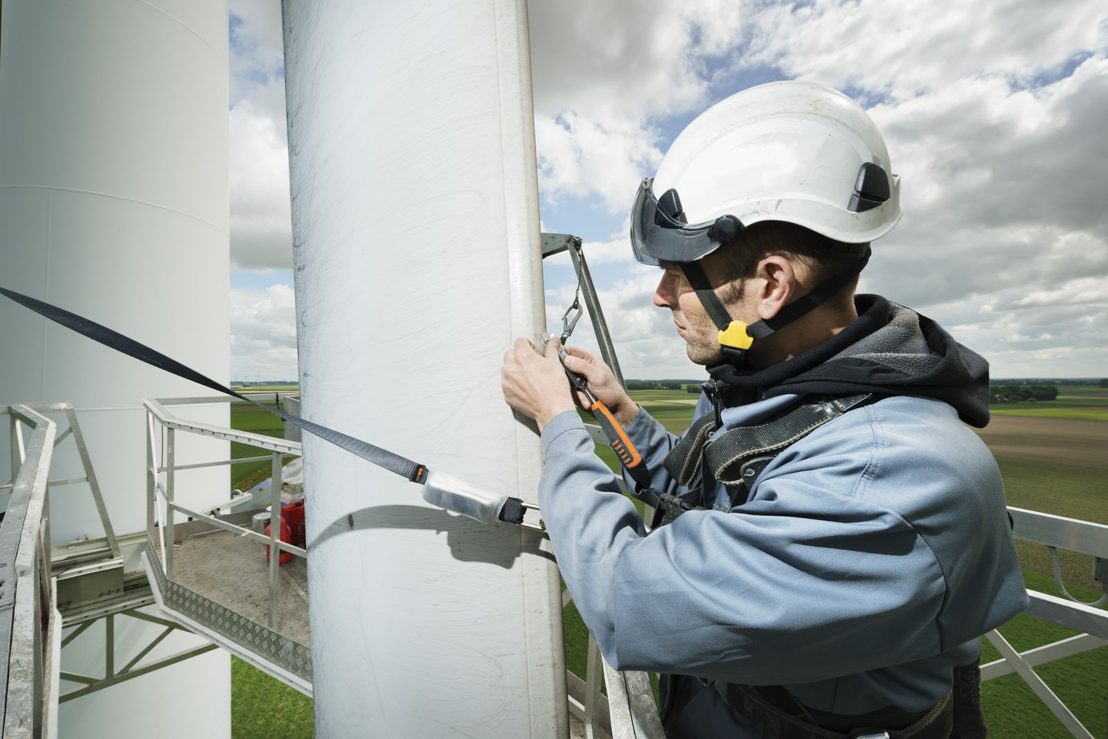 A technician on a service platform working on a wind turbine blade