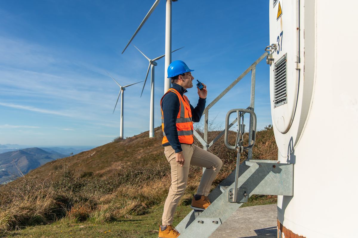 An engineer climbing a wind turbine tower using a two-way radio